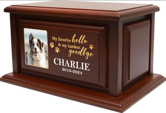 A dark brown wooden pet memorial urn with a custom photo of a dog and engraved gold and white text reading 'My favorite hello & my hardest goodbye CHARLIE 2010-2024' on a white background.