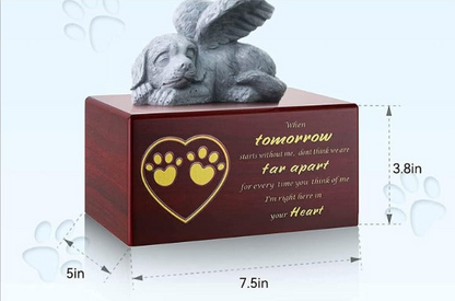 A pet memorial urn with a dark reddish-brown wooden box, featuring a gray winged dog figurine on top. The front of the box has a gold heart outline with yellow paw prints and engraved text.